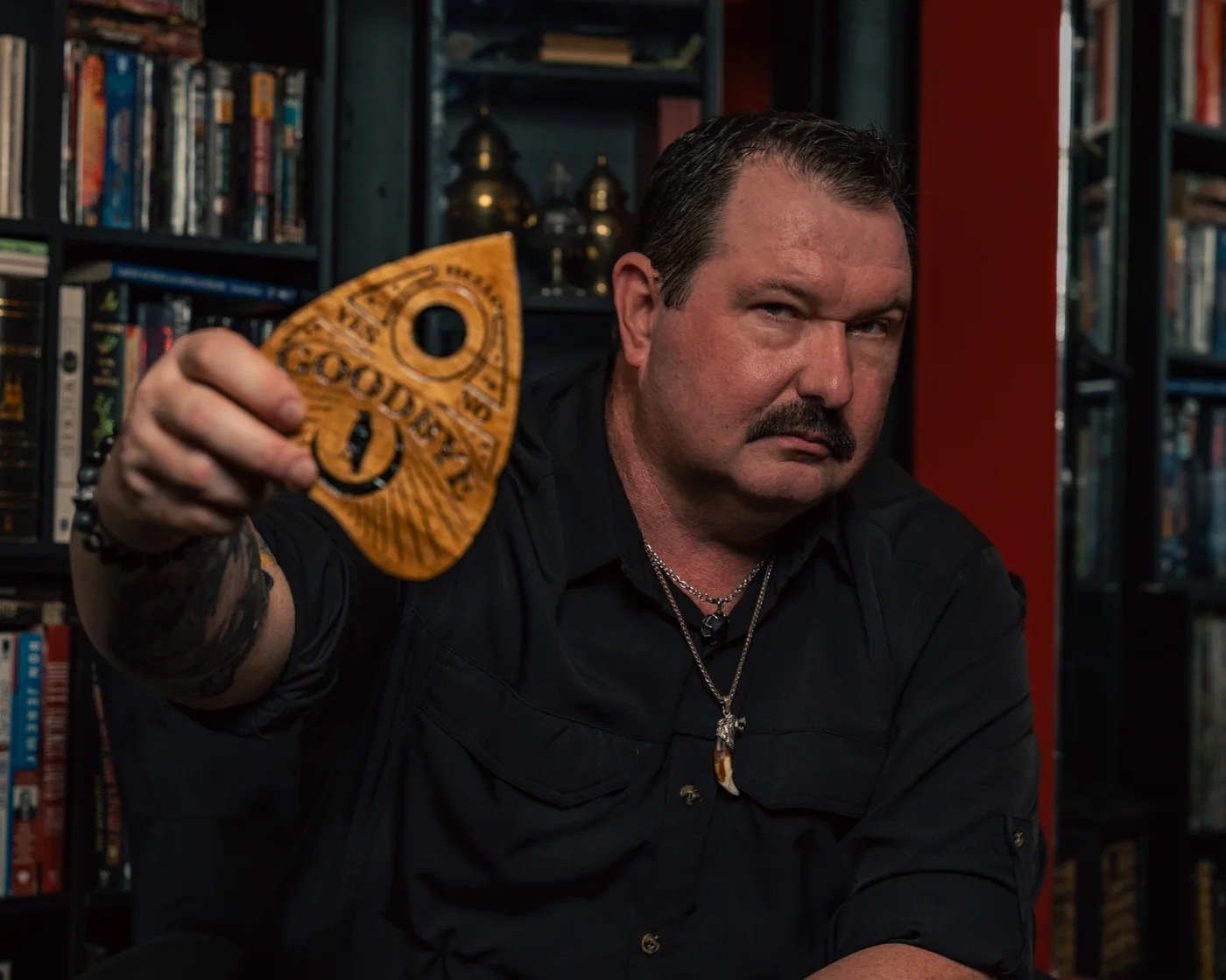 Matthew J. Sorge holding a Ouija planchette in a cinematic portrait
